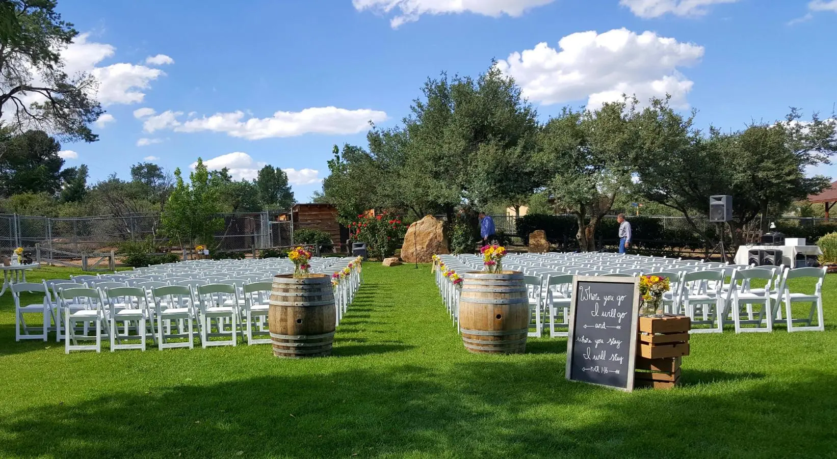 An outdoor wedding setup with chairs and a chalkboard sign